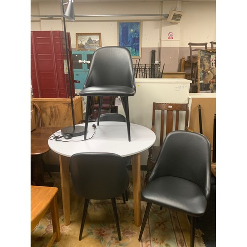 876 - A modern circular white dining table with four black chairs and standard lamp