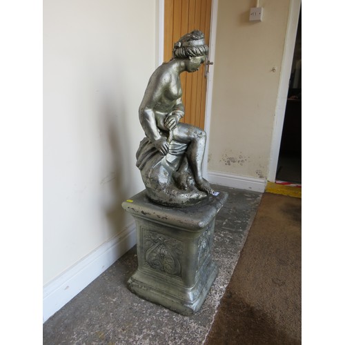 605A - A GARDEN STATUE ON PLINTH OF A FEMALE FIGURE SEATED ON A ROCK, H 94 cm