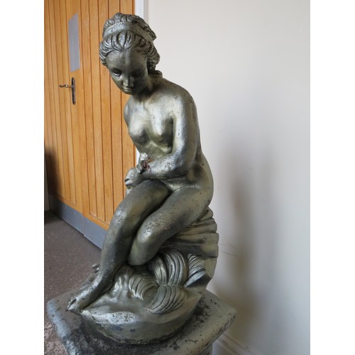 605A - A GARDEN STATUE ON PLINTH OF A FEMALE FIGURE SEATED ON A ROCK, H 94 cm