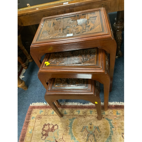 757 - A carved hardwood eastern nest of three tables with glass tops