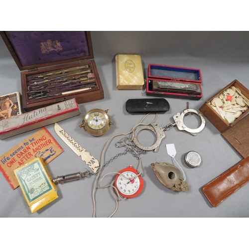 498 - A tray of assorted collectables to include vintage handcuffs, playing cards, cased instrument set, s... 