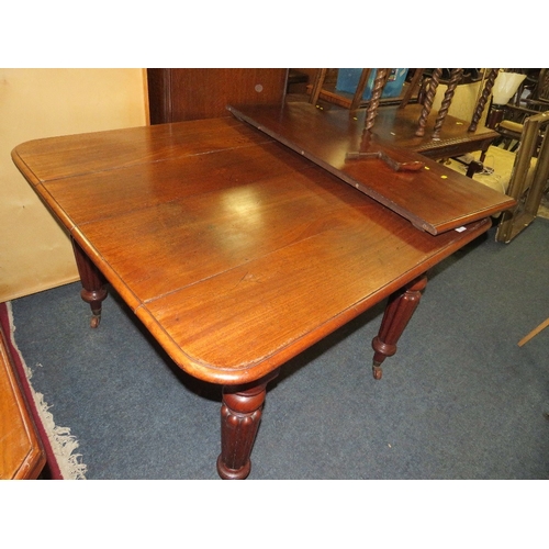 761 - A small Victorian mahogany wind-out dining table raised on fluted supports with a spare leaf - Handl... 