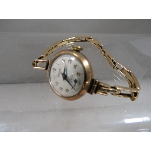 303 - A 9 carat gold wrist watch on an expandable yellow metal bracelet