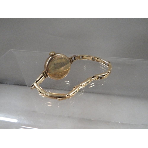 303 - A 9 carat gold wrist watch on an expandable yellow metal bracelet