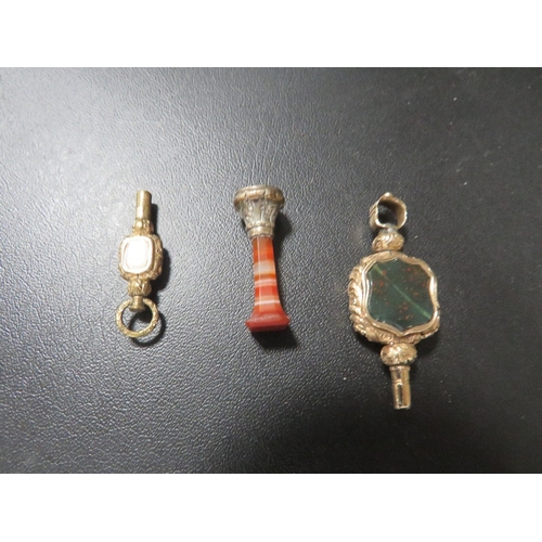 374 - A small hard stone column seal together with two jewelled yellow metal watch winders (3)