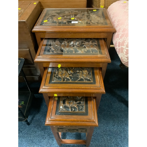 873 - An Eastern nest of four carved tables with glass tops