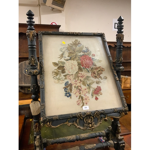 880 - A Victorian carved and gilded revolving fire screen, with two needle point panels depicting flowers ... 