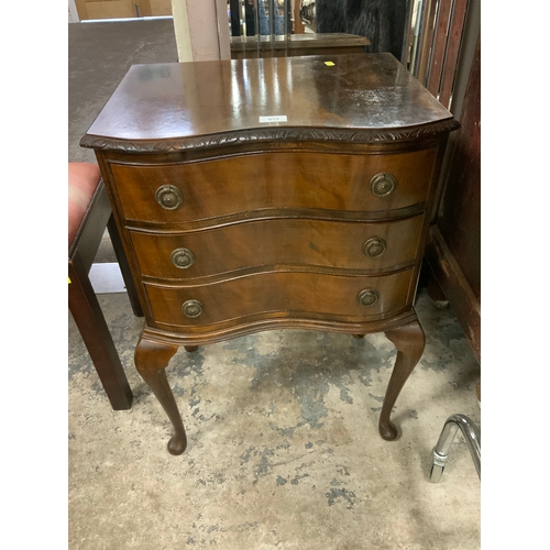 915 - A small three drawer walnut bedside chest raised on cabriole legs