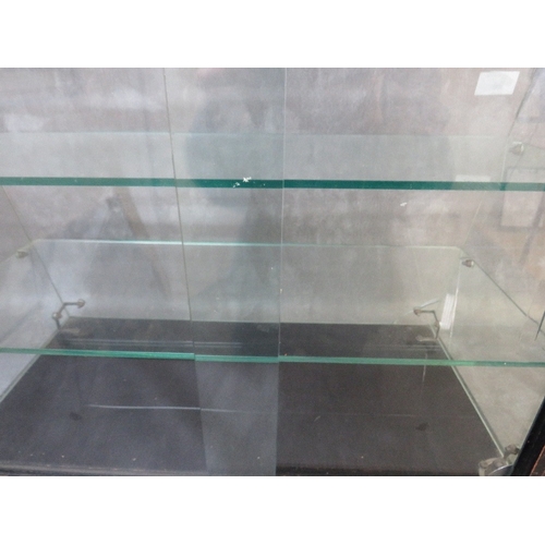 26 - A PLATE GLASS TWO SHELF SHOP DISPLAY CABINET WITH SLOPING FRONT, sliding doors to back, H 46 cm, W 6... 