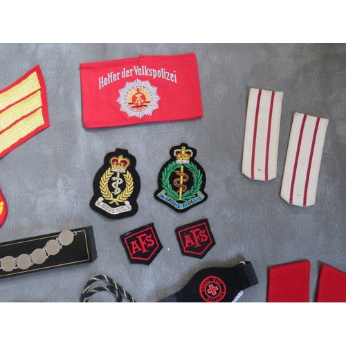 175 - A BOX OF ASSORTED CLOTH AND OTHER BADGES, to include Communist types, along with a GDR armband, a 19... 