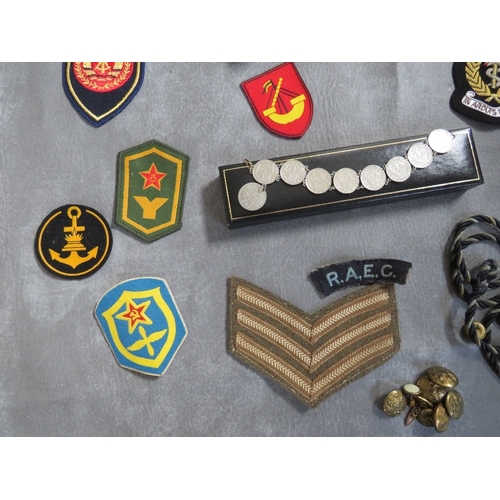 175 - A BOX OF ASSORTED CLOTH AND OTHER BADGES, to include Communist types, along with a GDR armband, a 19... 