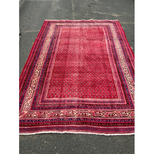 828 - A large red Eastern woollen rug 320 x 210 cm