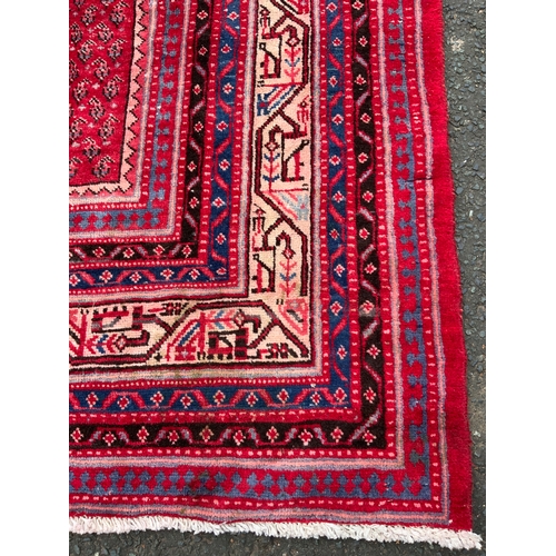 828 - A large red Eastern woollen rug 320 x 210 cm