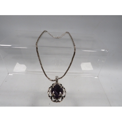 431 - A decorative silver pendant on chain set with a purple stone