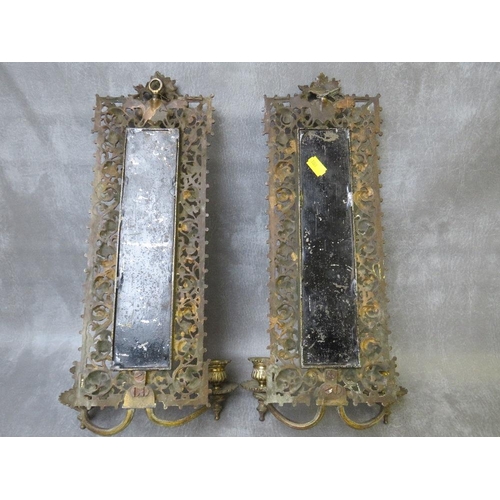 868 - A PAIR OF EARLY 20TH CENTURY BRASS PIERCED MIRRORED WALL SCONCES, each with a pair of candle holders... 