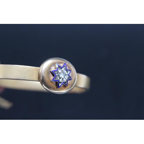 643 - A 15CT DIAMOND AND ENAMEL BANGLE, having a central diamond surrounded by 8 diamonds and these in tur... 