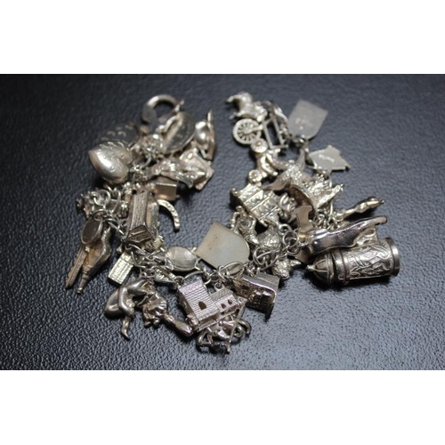 627 - A HEAVY SILVER CHARM BRACELET, festooned with many charms, approx weight 107.6g