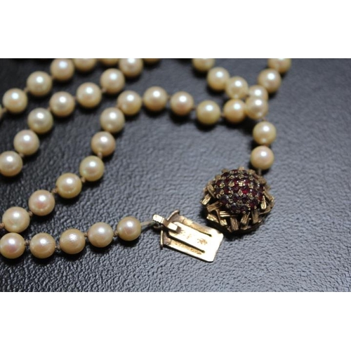 672 - A LONG STRAND OF INDIVIDUALLY KNOTTED FRESHWATER CULTURED PEARLS ON A DOMED 9ct GARNET SET FASTENING... 