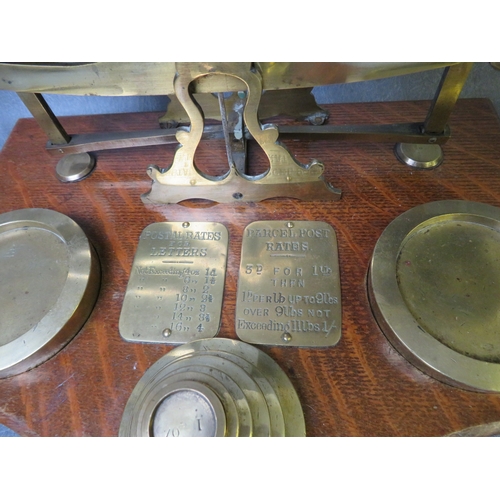 852 - A VINTAGE SET OF POST OFFICE BRASS SCALES, on a wooden base, together with a set of brass weights, L... 