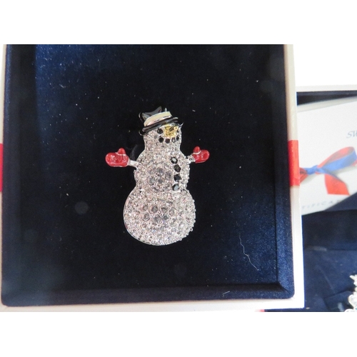 557 - TWO BOXED SWAROVSKI CHRISTMAS THEMED BROOCHES, comprising a Christmas tree - H 5.5 cm and a snowman,... 