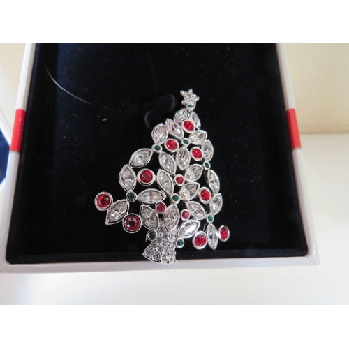 557 - TWO BOXED SWAROVSKI CHRISTMAS THEMED BROOCHES, comprising a Christmas tree - H 5.5 cm and a snowman,... 