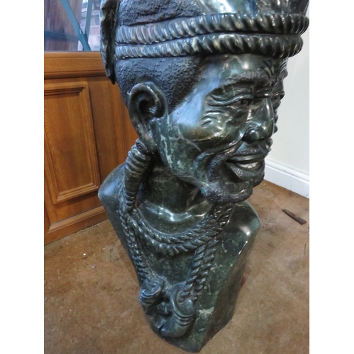 1186 - AN AFRICAN CARVED STONE SCULPTURE DEPICTING A TRIBAL MAN IN TRADITIONAL ATTIRE, 'Zulu King'  includi... 