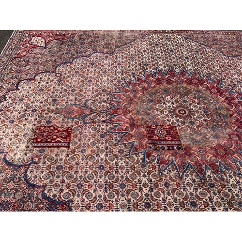 703 - A large Eastern woollen rug - mainly red and black, 333 x 245 cm A/F
