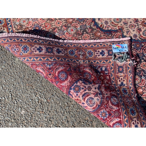 703 - A large Eastern woollen rug - mainly red and black, 333 x 245 cm A/F