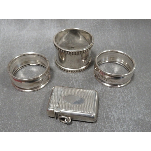 304 - A hallmarked silver vesta case together with three hallmarked silver napkin rings