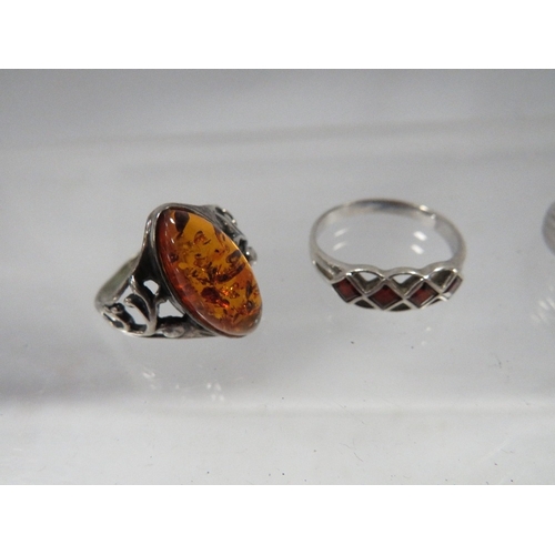 328 - Four dress rings to include a silver amber style example