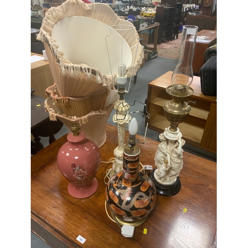 A vintage figurative oil lamp together with three large table lamps and assorted shades. (4)