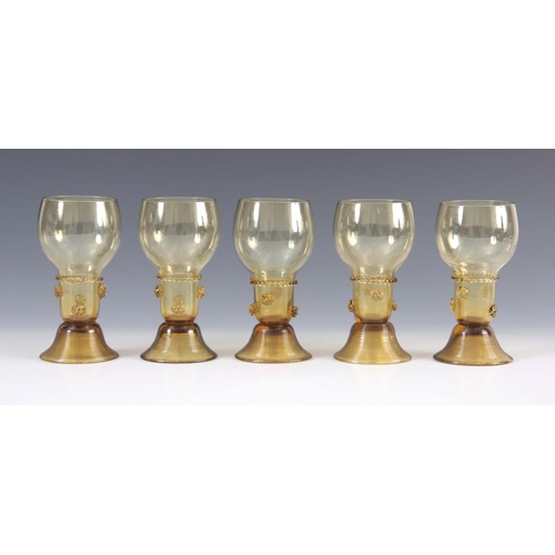 10 - A SET OF 5 CONTINENTAL PALE AMBER WINE GLASSES with rounded bowls and prunted stems on ribbed spread... 