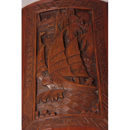 126 - A CARVED CHINESE HARDWOOD SHAPED BLANKET BOX decorated with figures amongst trees and galleons 102cm... 