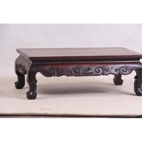 138 - A 19TH CENTURY CHINESE HARDWOOD LOW OCCASIONAL TABLE with panelled top and shaped scroll carved base... 