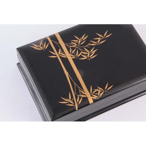 151 - A 20TH CENTURY JAPANESE EBONISED LAQUERED BOX decorated with gilt bamboo design to the lid - signed ... 