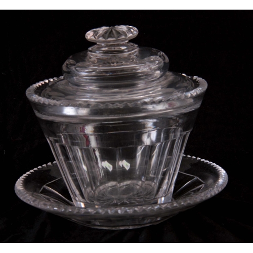 17 - AN ANGLO IRISH GEORGIAN CUT GLASS LIDDED BUTTER DISH AND STAND,15cm high by 16.5 cm wide.