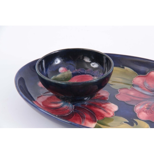 41 - A MID 20TH CENTURY WALTER MOORCROFT OVAL HIBISCUS PLATE on a blue ground  23cm by 15.5cmTOGETHER WIT... 