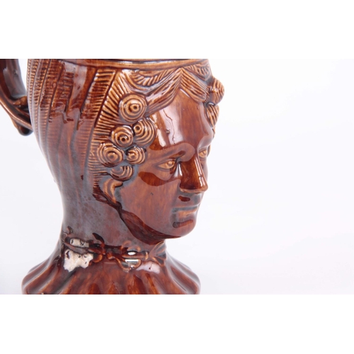 64 - A 19TH CENTURY TREACLE GLAZED POTTERY MUG moulded in the form of a ladies head, 15cm high by 16cm wi... 