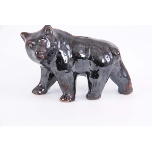 65 - A 19TH CENTURY TREACLE GLAZED POTTERY MONEY BOX IN THE FORM OF A BEAR, 12cm high by 18cm wide.