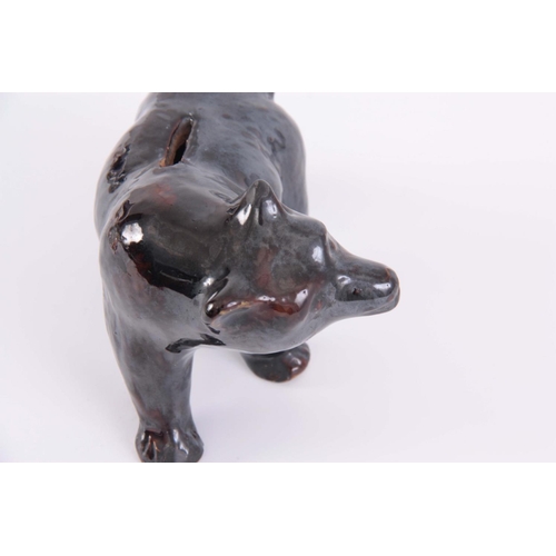 65 - A 19TH CENTURY TREACLE GLAZED POTTERY MONEY BOX IN THE FORM OF A BEAR, 12cm high by 18cm wide.