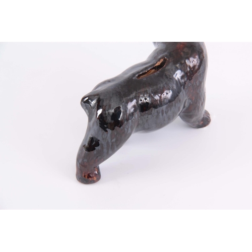 65 - A 19TH CENTURY TREACLE GLAZED POTTERY MONEY BOX IN THE FORM OF A BEAR, 12cm high by 18cm wide.