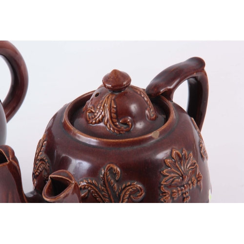 66 - TWO  UNUSUAL 19TH CENTURY TEAPOTS, one being an oversized double spouted treacle glazed decorated wi... 