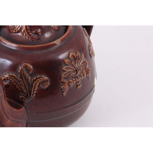 66 - TWO  UNUSUAL 19TH CENTURY TEAPOTS, one being an oversized double spouted treacle glazed decorated wi... 