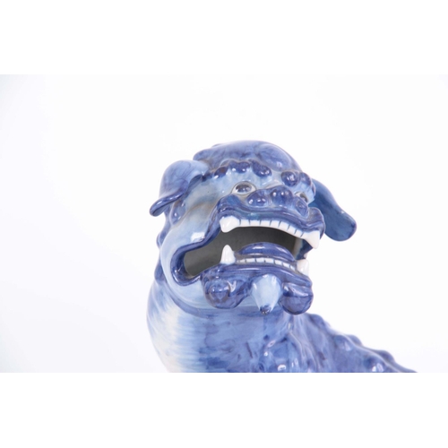 77 - AN 18TH/19TH CENTURY DELFT BLUE AND WHITE FOO DOG FIGURE standing on a pierced base having an old le... 