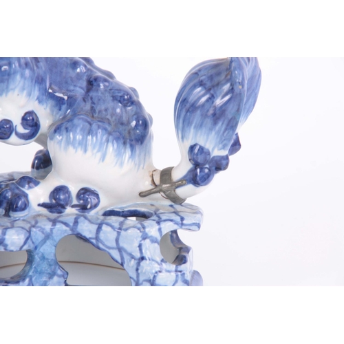 77 - AN 18TH/19TH CENTURY DELFT BLUE AND WHITE FOO DOG FIGURE standing on a pierced base having an old le... 