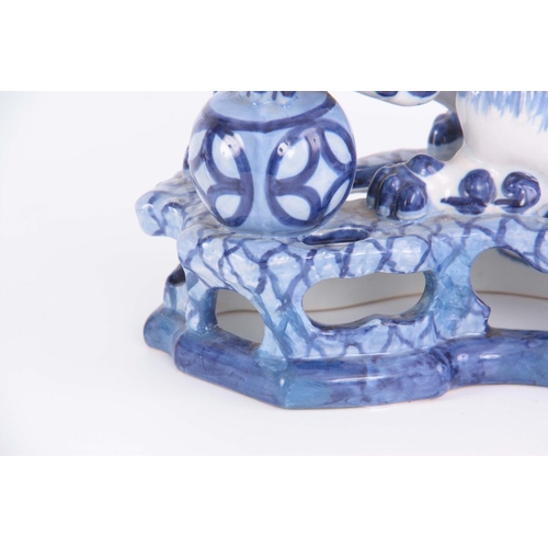 77 - AN 18TH/19TH CENTURY DELFT BLUE AND WHITE FOO DOG FIGURE standing on a pierced base having an old le... 