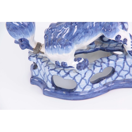 77 - AN 18TH/19TH CENTURY DELFT BLUE AND WHITE FOO DOG FIGURE standing on a pierced base having an old le... 