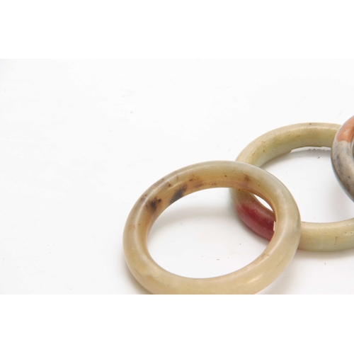 197 - THREE CHINESE RUST JADE BANGLES 92mm, 93mm and 90mm diameter overall.