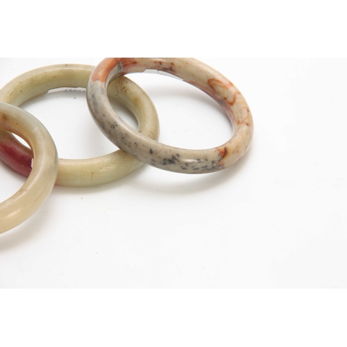 197 - THREE CHINESE RUST JADE BANGLES 92mm, 93mm and 90mm diameter overall.