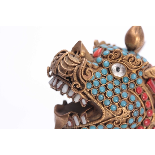 207 - AN ORIENTAL GILT BRASS BUDHISTIC DRAGON LION with jewelled coral coloured and turquoise decoration s... 